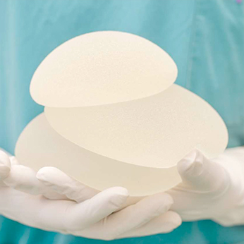 Photo de deux mains portant des implants mammaires